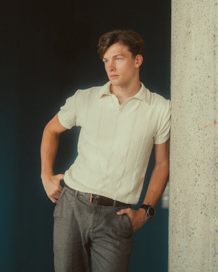 services-img A young man in Berlin posing casually in smart casual attire, leaning against a concrete wall.