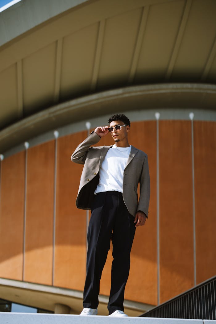 our-services-2 A fashionable man wearing sunglasses poses in front of a modern building in Berlin, emphasizing urban style.