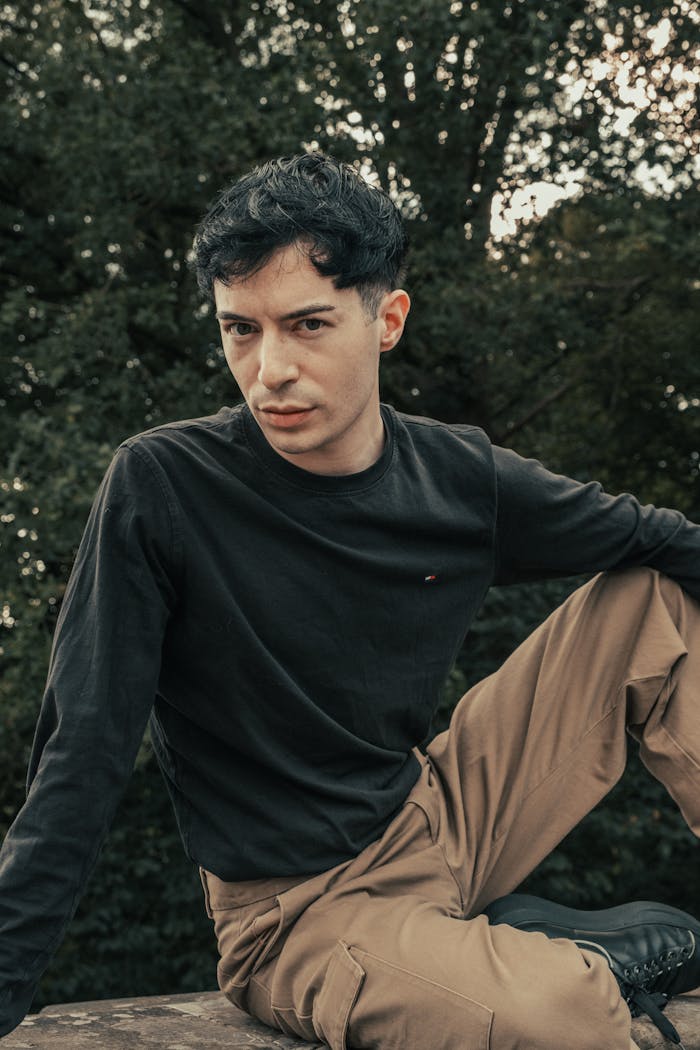 gallery-4 A young man in beige cargo pants and a black sweatshirt posing confidently outdoors.