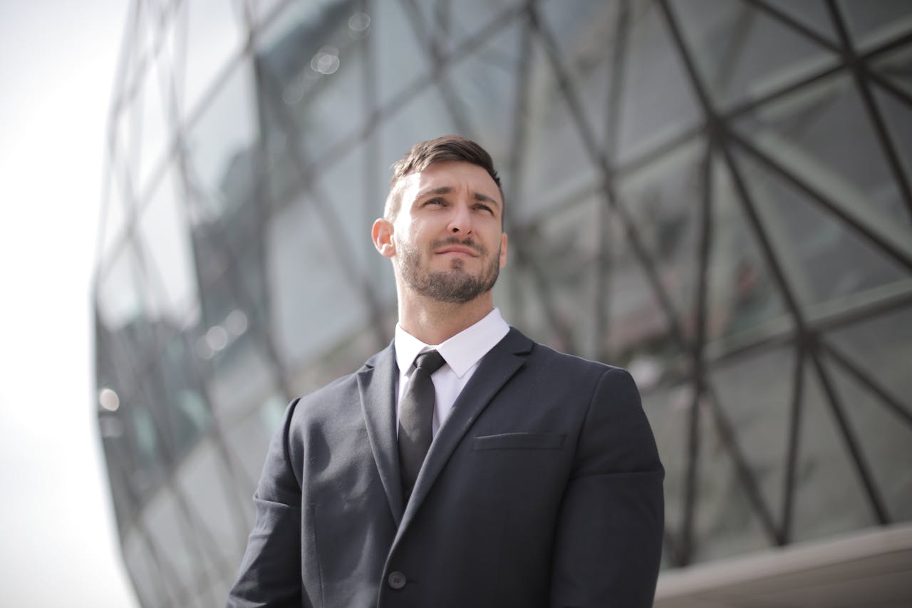 services-02 Portrait of a confident businessman in a suit standing outside a modern office building.
