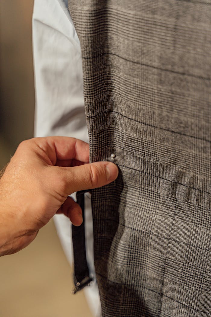 services-03 A hand adjusting a button on a tailored suit jacket, focusing on detail.