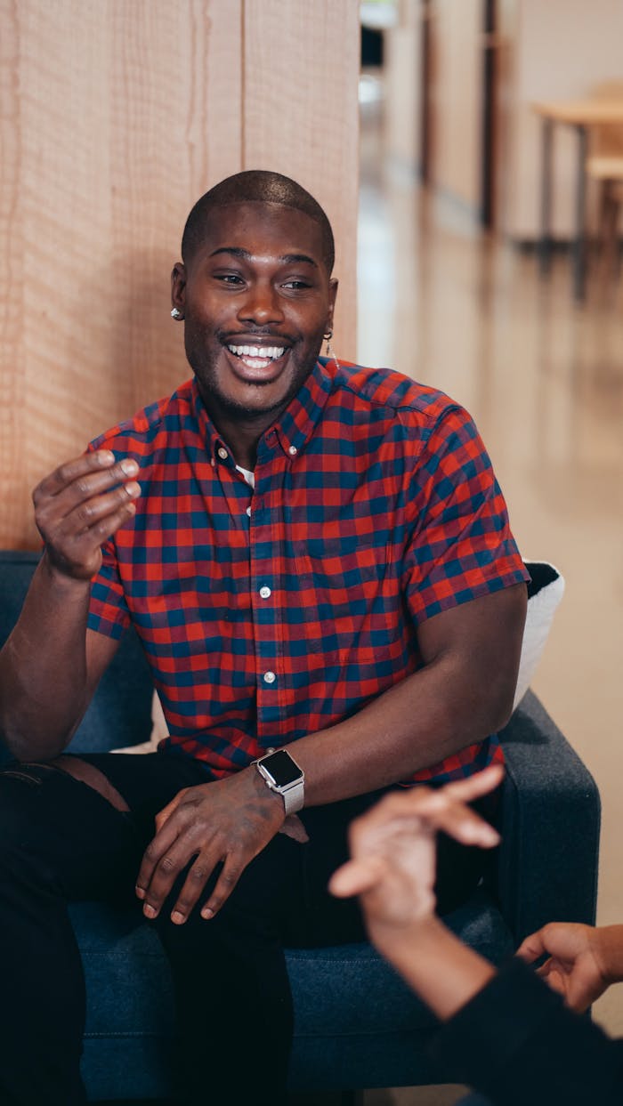 ours-journey A joyful man in a plaid shirt smiles during a friendly chat, showcasing positive interactions.