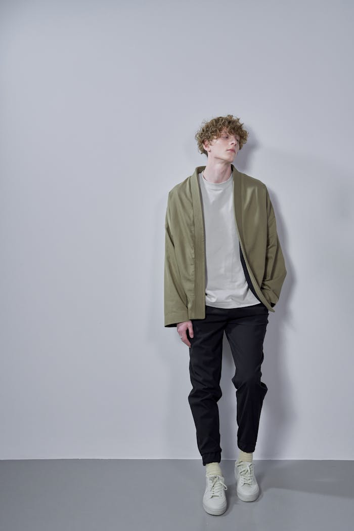 Contemporary portrait of a young man with stylish outfit against a neutral gray background.